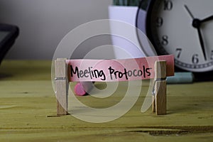 Meeting Protocols. Handwriting on sticky notes in clothes pegs on wooden office desk