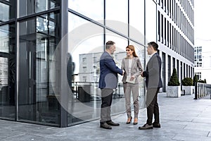 Meeting of three colleagues from outside the office building, experienced and mature IT specialists