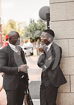 Meeting of two long-time friends of black African American businessman in suits outdoors