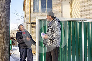 Meeting of two mature neighbors at the gate of a rural house