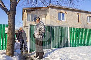 Meeting of two mature neighbors at the gate of a rural house