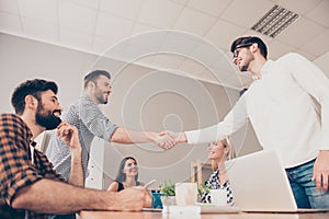 At a meeting young businessmen shake hands to each other