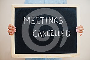 Meetings cancelled. Coronavirus concept. Boy hold inscription on the board
