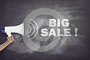 Megaphone with big sale sign on blackboard