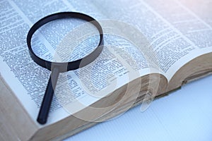 Megnifying glass on page of dictionary.