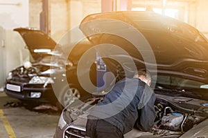 Mehanic doing check-up under opened car hood. Tools over dirty motor room. Car service and maintenance.Toned