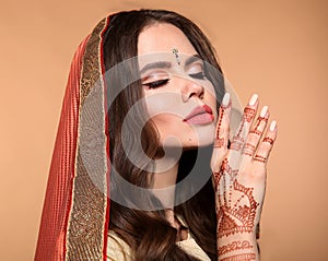 Mehndi. Portrait of beautiful girl in saree isolated on beige. Young hindu woman model with kundan golden jewelry set. Traditional