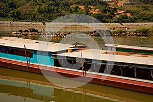 Mekong river, Laos and Thailand at Huay Xai. Traditional wooden boats at sunset