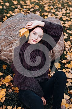 Melancholic beautiful young woman sitting in autumn park