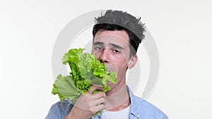 Melancholic Caucasian Man Eating Lettuce Leaf on White Background
