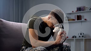 Melancholic male soldier holding toy dog, missing child after divorce, lonely