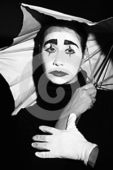 Melancholic mime with umbrella.