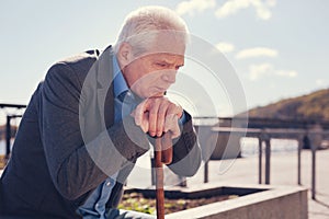 Sorrowful elderly man sitting on the bridge