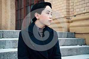 Melancholic portrait of young asian woman with short hair style sitting on the stairway