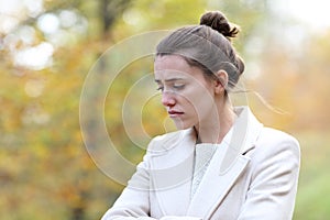 Melancholic sad woman looking down in a park in winter