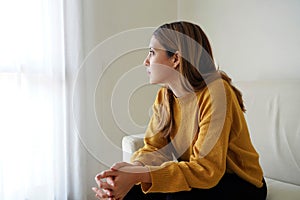 Melancholic sad woman looking through the window at home