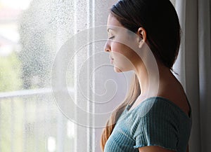 Melancholic sad woman with low gaze at home in a rainy day, focus on the model eyes, indoor photo