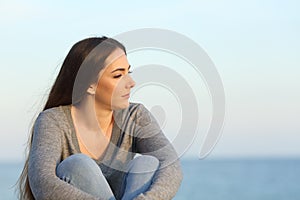 Melancholic woman looks away on the beach