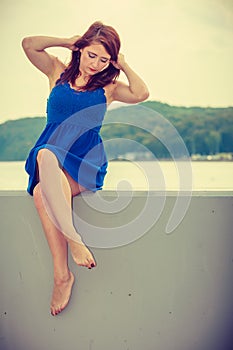 Melancholic woman in short dress sitting on jetty