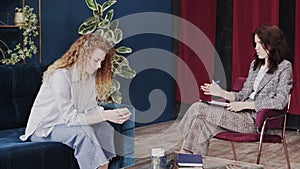 Melancholic woman with wipe in hands talking with psychologist at therapy session, depression