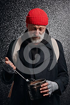 Melancholy homeless man trying to find some food in pan