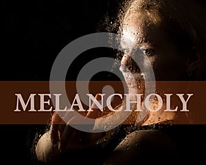 Melancholy written on virtual screen. hand of young woman melancholy and sad at the window in the rain