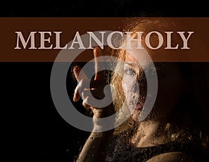 Melancholy written on virtual screen. hand of young woman melancholy and sad at the window in the rain