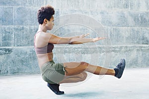 Melanesian pacific islander athlete girl with afro performing exercising routines sitting plank