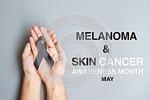 Melanoma and skin cancer, Vaccine injury awareness month and rest in peace concepts. Man holding black Ribbon on grey background