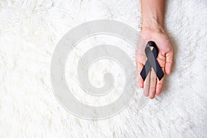 Melanoma and skin cancer, Vaccine injury awareness month and rest in peace concepts. Man holding black Ribbon on white bed