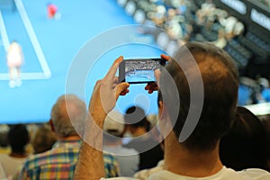 Unidentified spectator uses his cell phone to take images during tennis match at 2019 Australian Open in Melbourne Park