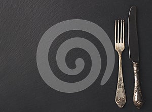 Melchior spoon and fork on the black stone background photo