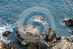 MELLIEHA, MALTA - 01 JAN, 2020: A man sitting on a rock near the ocean on the island of Malta during calm sea