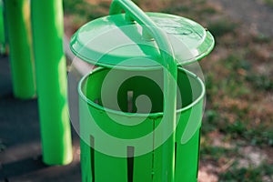 A mellifluous green trash can in the park. New, minimalist trash can. Environmental protection. Space for text photo