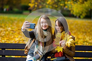 Mellow autumn. Two cute students makes a selfie in the park.