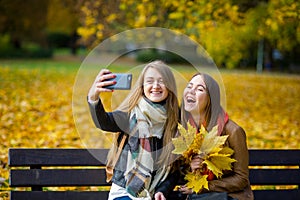 Mellow autumn. Two cute students makes a selfie in the park.