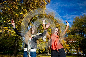 Mellow autumn. Two girls are students cheerfully spend time in the city park.