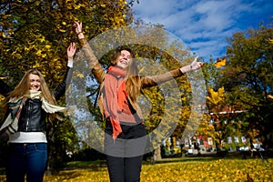 Mellow autumn. Two girls are students cheerfully spend time in the city park.