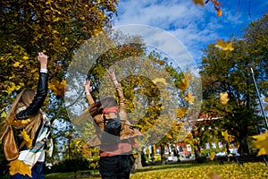 Mellow autumn. Two girls are students cheerfully spend time in the city park.