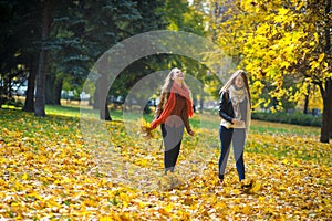 Mellow autumn. Two girls are students cheerfully spend time in the city park.