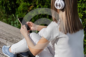 Melodies and Style: Girl in Striped Pants Enjoying Music and Technology in the Park