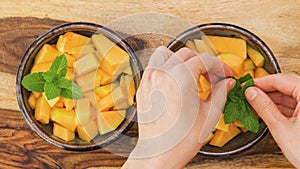 Melon fruit salad with mint leaves close up in bowls, woman hands