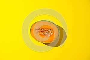 Melon in harsh sunlight on a yellow background. Juicy ripe summer fruit. Free space for text.