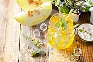 Melon lemonade in glasses with ice and mint on a wooden rustic table. Fresh refreshing fruity summer drink, seasonal beverages