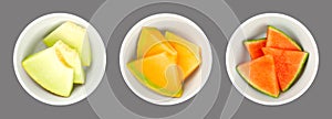 Melon slices, fresh melon pieces in white bowls, over gray