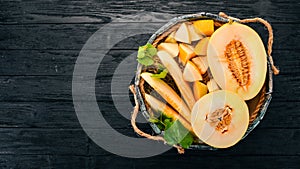 Melon in a wooden box. Sliced to pieces of melon. On a wooden background. Free space for text.