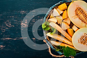 Melon in a wooden box. Sliced to pieces of melon. On a wooden background. Free space for text.