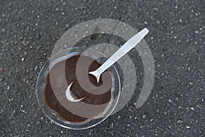 Melted Chocolate Ice Cream Cup and Spoon on Asphalt