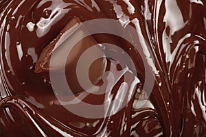 Melted chocolate and pieces of chocolate bar as a background closeup