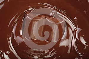 Melted chocolate and pieces of chocolate bar as a background closeup